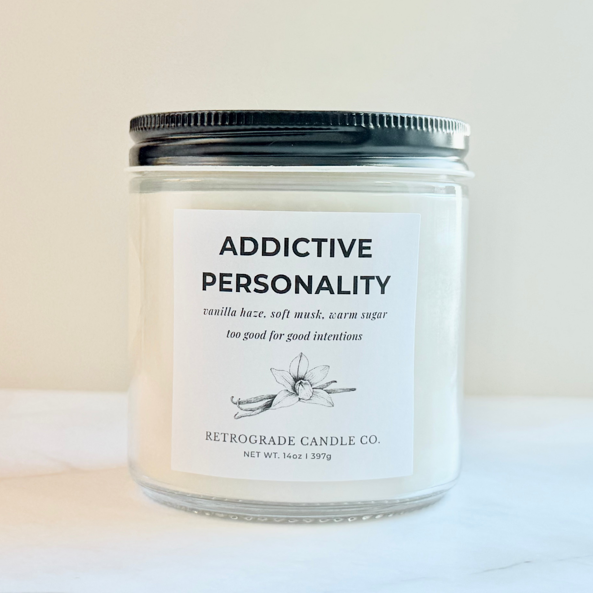 Candle jar labeled 'Addictive Personality' by Retrograde Candle Co. on a light background
