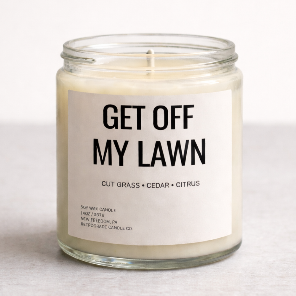 Candle in a glass jar with a label reading 'Get Off My Lawn' on a light background
